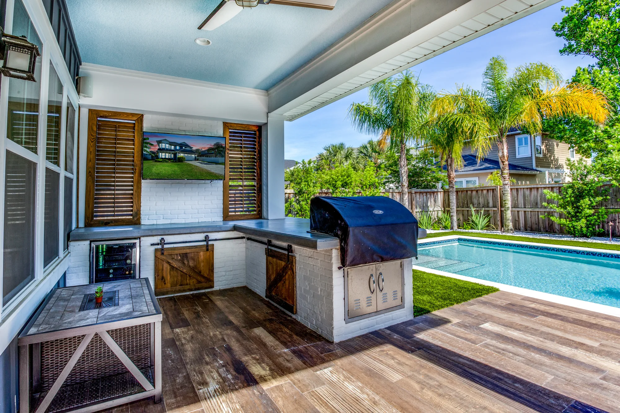 Covered patio with a custom outdoor kitchen, built-in grill, pool and artificial turf in a remodeled San Diego backyard