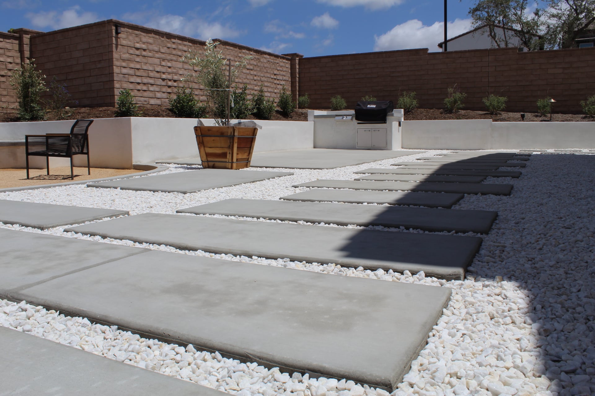 Poured concrete pads set in chip stone beside a seat wall and a built-in island