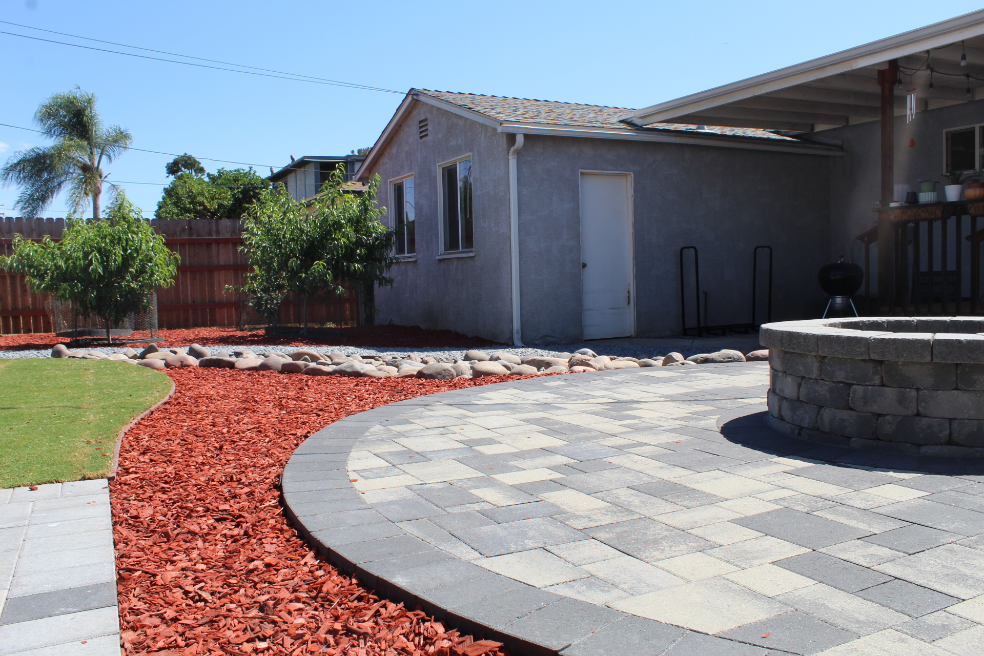 Fire pit and paver medallion seen across the finished backyard