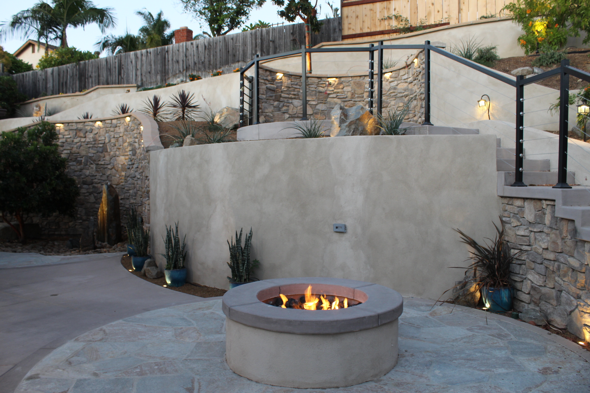 Spring Valley terrace at twilight with the fire pit lit and cafe string lights overhead