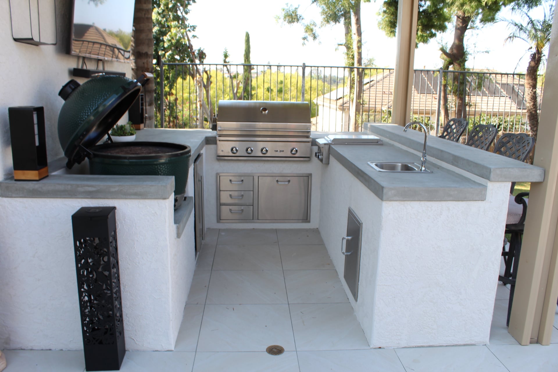 Stainless built-in grill and kamado set into a white stucco outdoor kitchen island