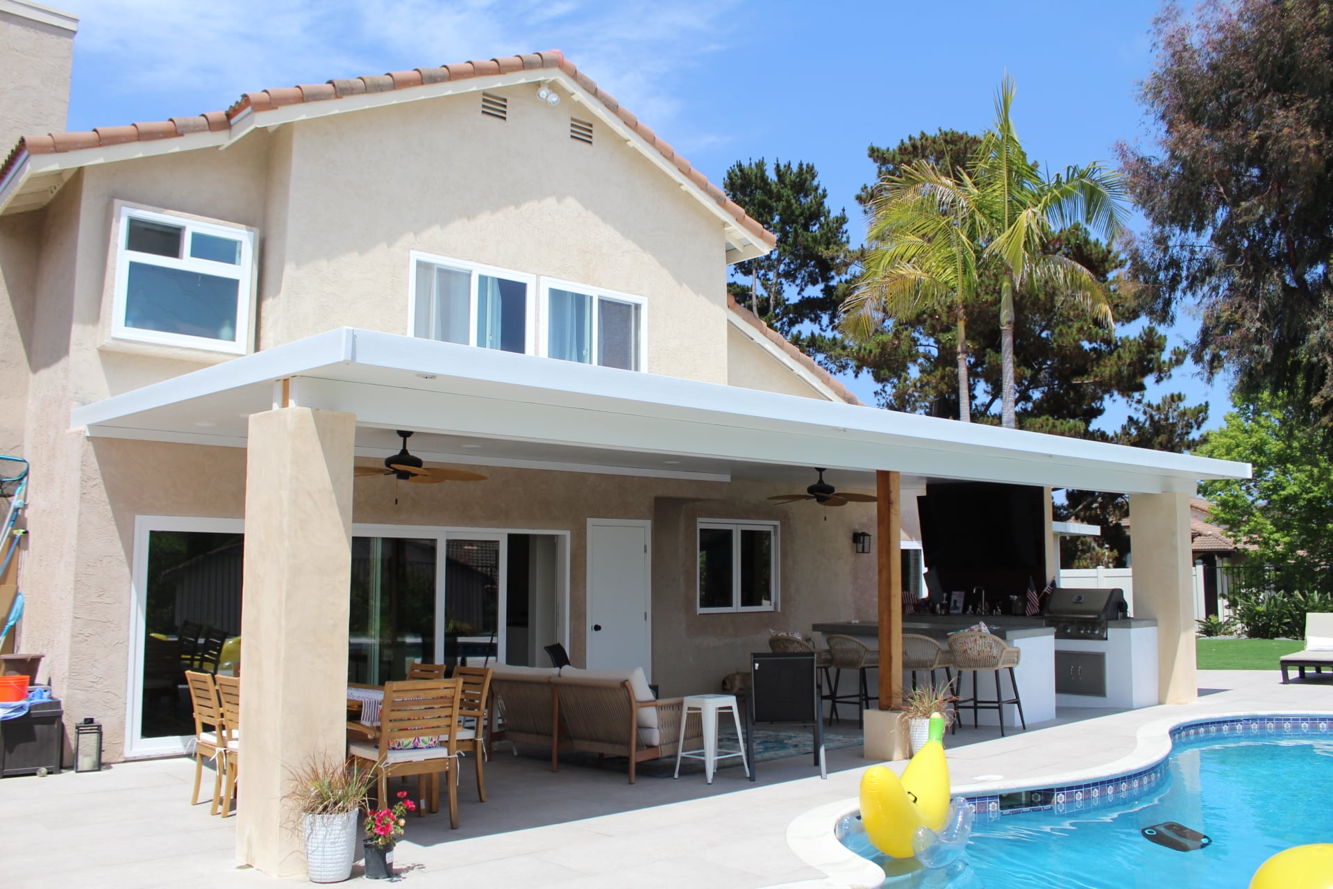 Encinitas patio cover spanning the rear elevation above dining and lounge seating by the pool deck