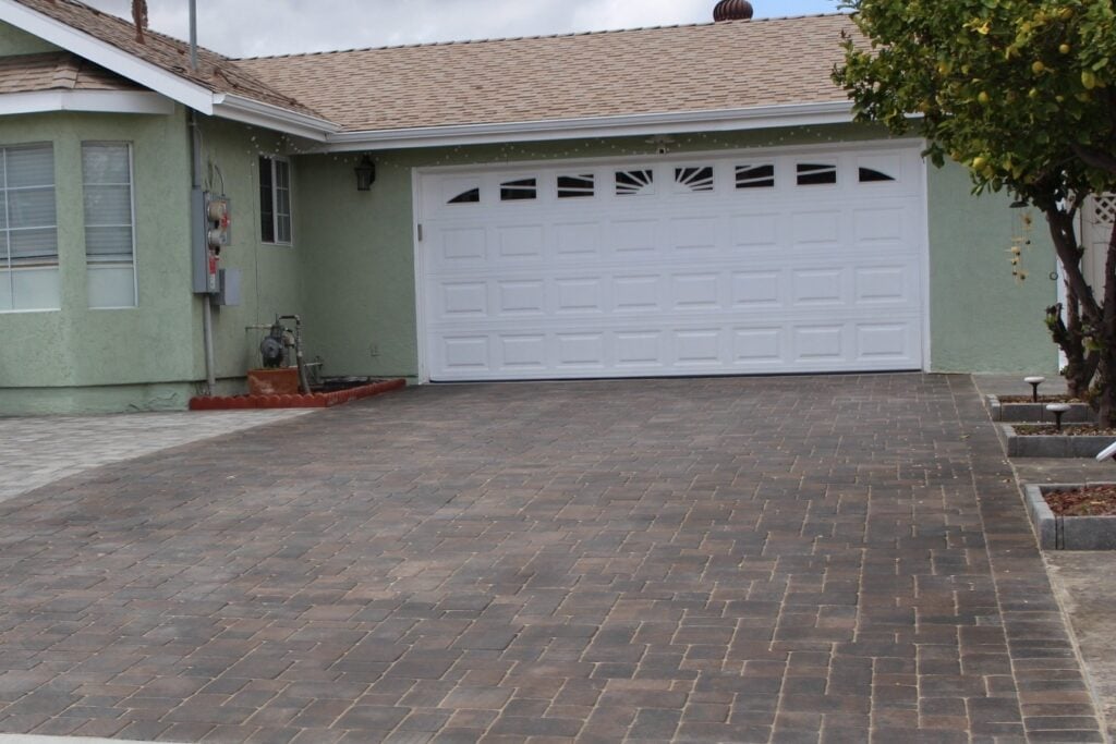Interlocking paver driveway leading to a white garage door