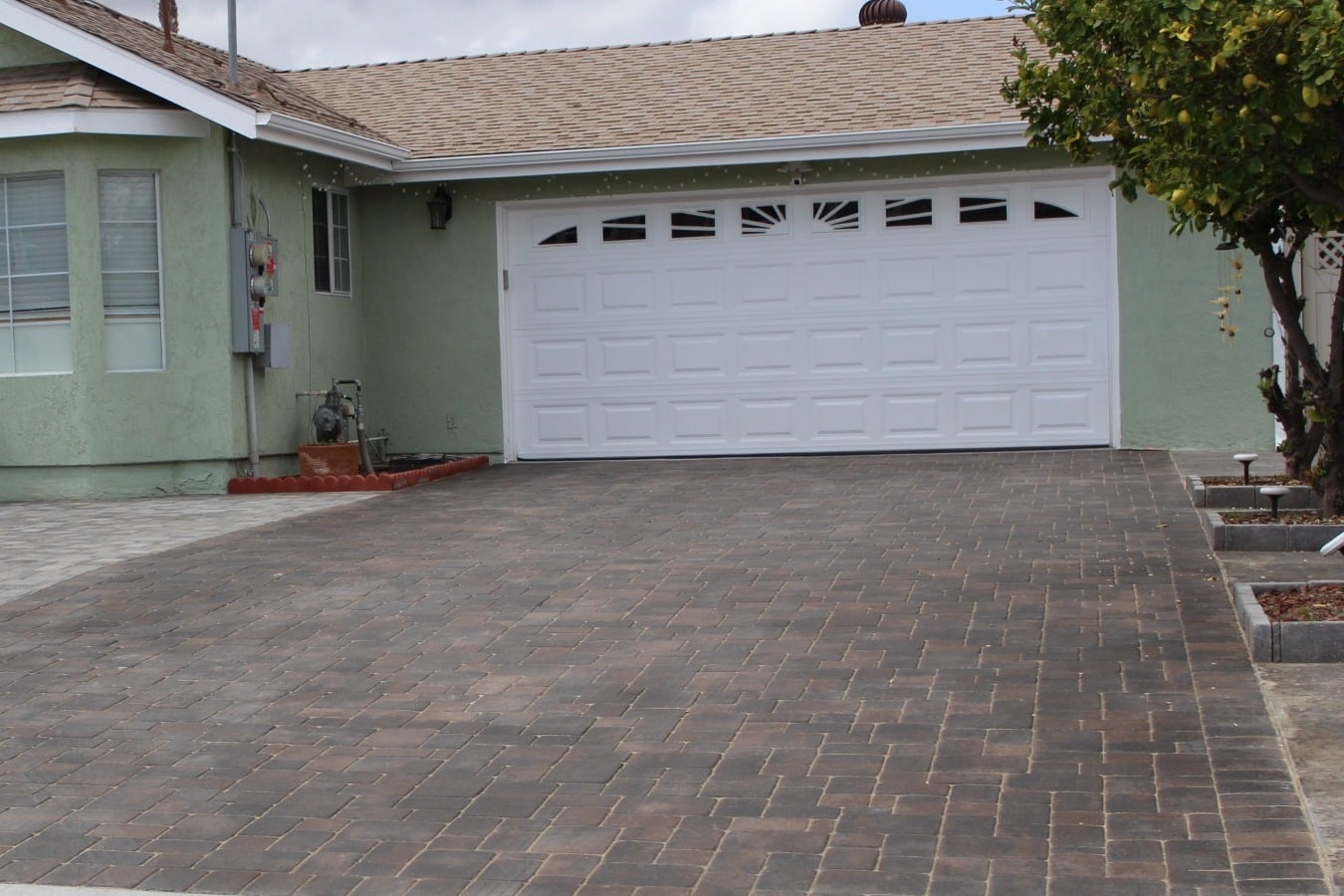 Interlocking paver driveway leading to a white garage door